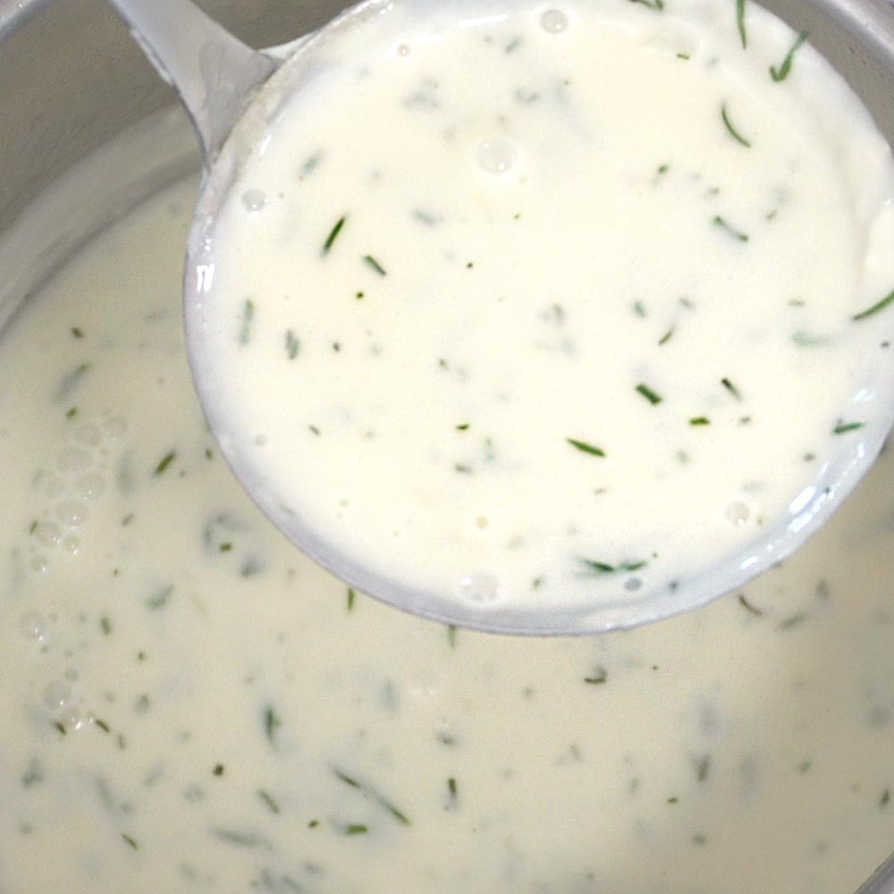 Dillsoße zu Fisch Rezept Lachs Dillsoße zu Fisch in der Soßenkelle über dem Kochtopf