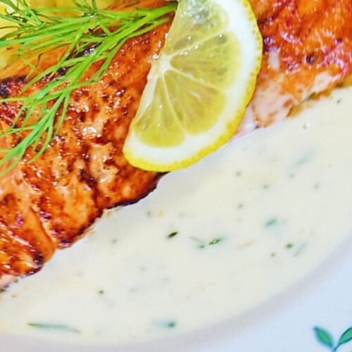 Leckeres Lachsfilet mit einer feinen samtigen Dillsauce nappiert und Zitrone garniert