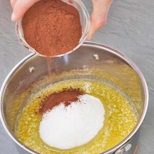 Zucker und Kakao-Pulver auf Butter geben